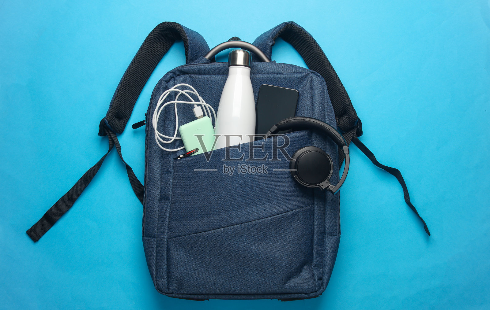 现代小工具和配件的工作和学习在背包粉红色的背景。前视图。平躺照片摄影图片