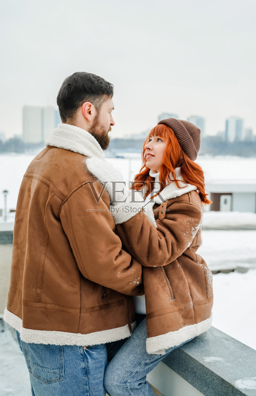 爱情浪漫的情侣爱情故事。残忍的大胡子男人,明亮的红发女孩在冬季公园。浪漫的约会,亲吻,拥抱。散步,玩得开心。时尚的服装,红色羊皮大衣,夹克,帽子照片摄影图片