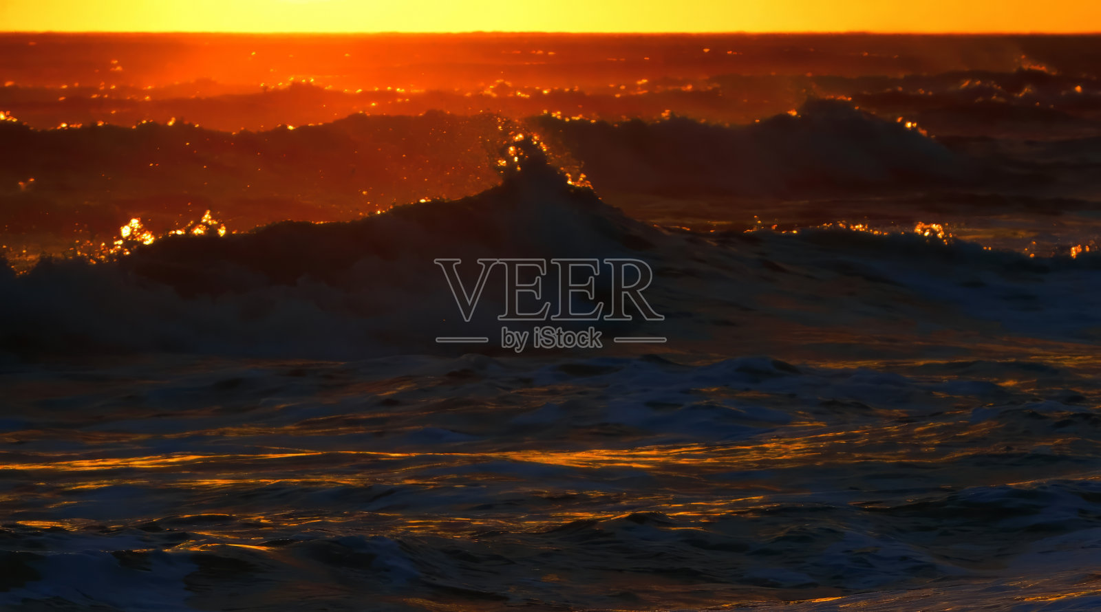 在夕阳的照耀下,海洋里形成了狂暴的波浪照片摄影图片