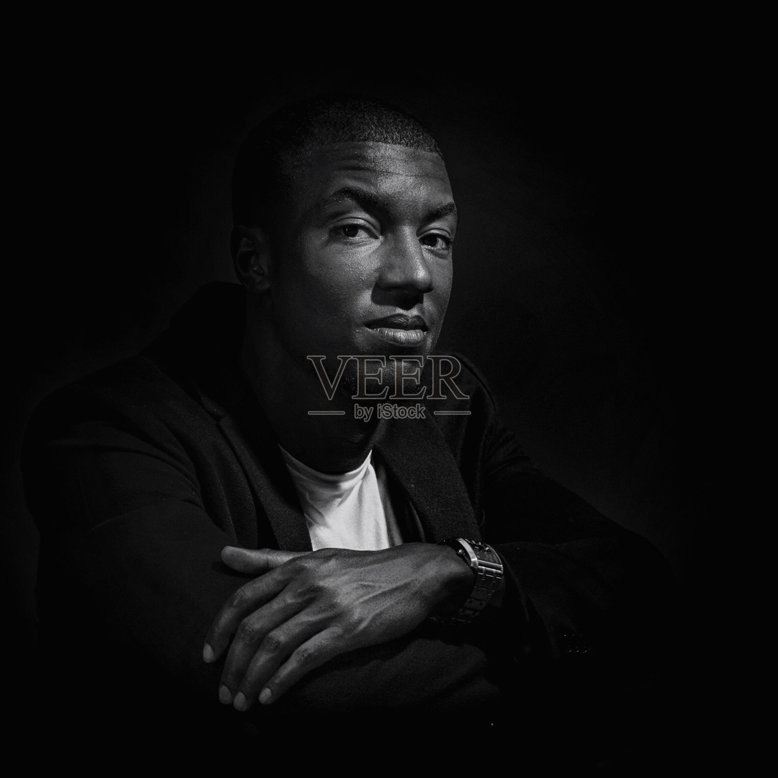 在黑色背景下,年轻自信的男子双臂交叉的肖像照片摄影图片