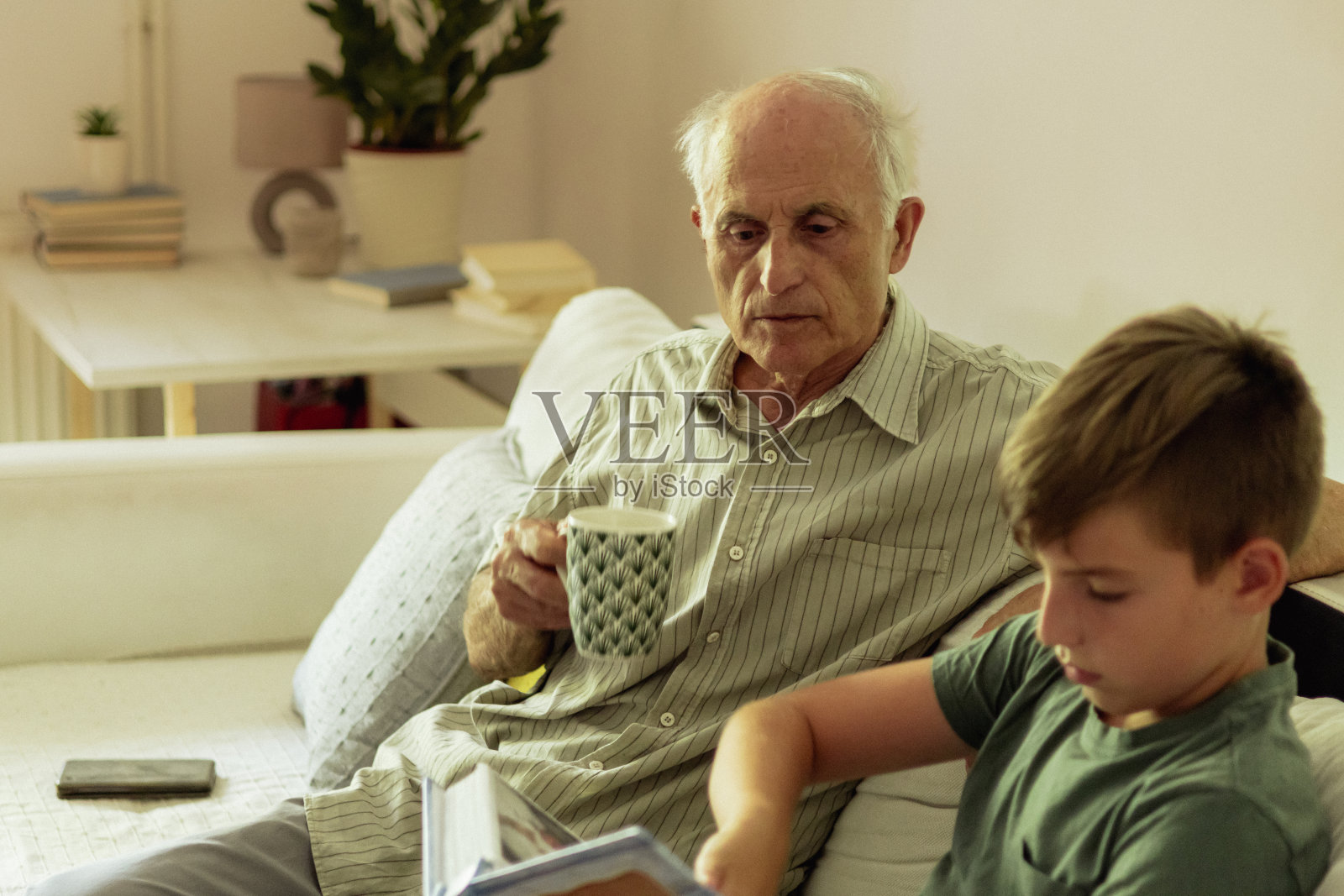 Grandfatherhood。开心的爷爷和孙子正在客厅看全家福相册。照片摄影图片