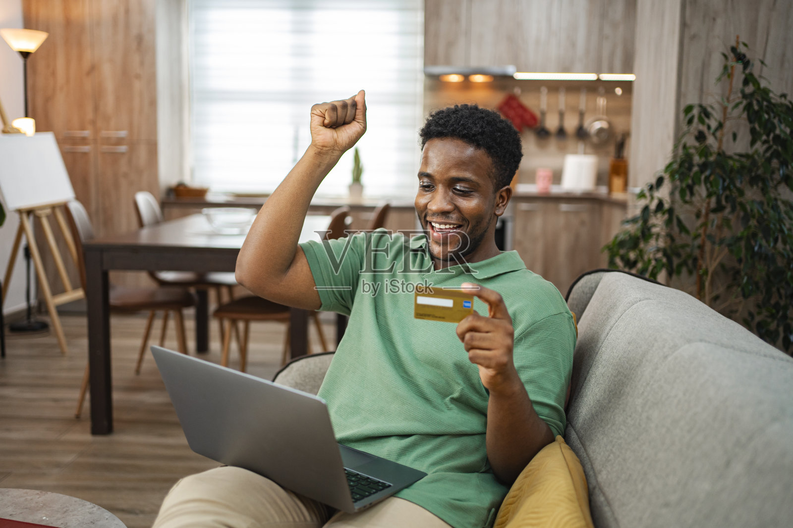 兴奋的黑人坐在家里的沙发上用笔记本电脑上网购物照片摄影图片