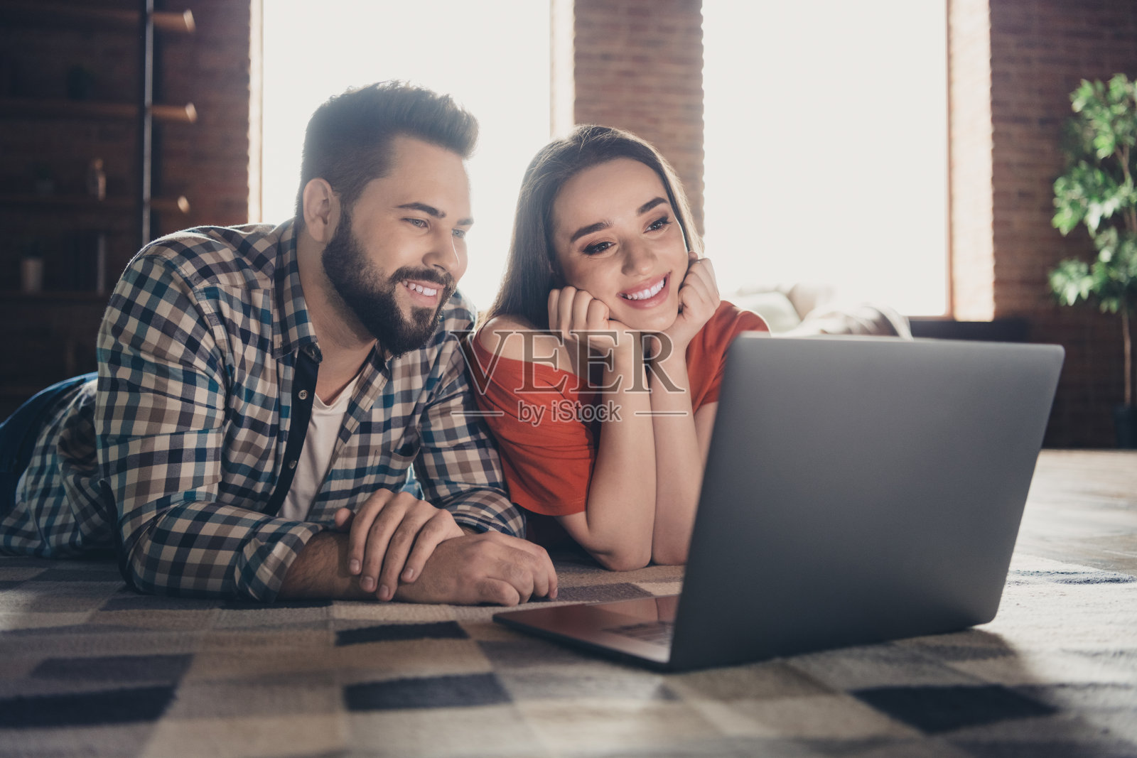 吸引人的欢快躺在地板上的照片上网本电子商务已婚的年轻夫妇花空闲时间搬新公寓,家庭室内室内照片摄影图片