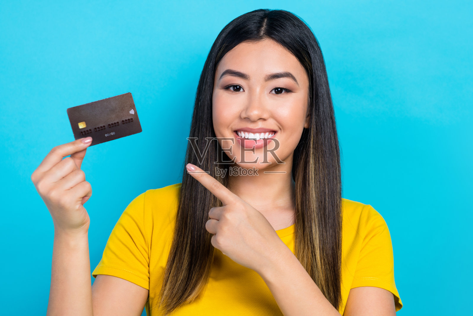 肖像的牙齿微笑的女人染的发型穿着时髦的t恤,表明在蓝色的背景上孤立的借记卡照片摄影图片