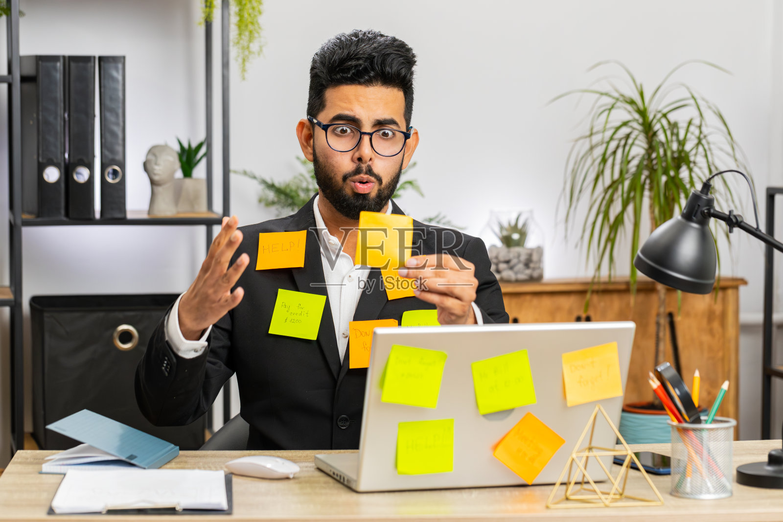 在办公室用笔记本电脑处理许多贴纸任务的商人,感到疲倦、悲伤、疲惫,恐慌发作照片摄影图片