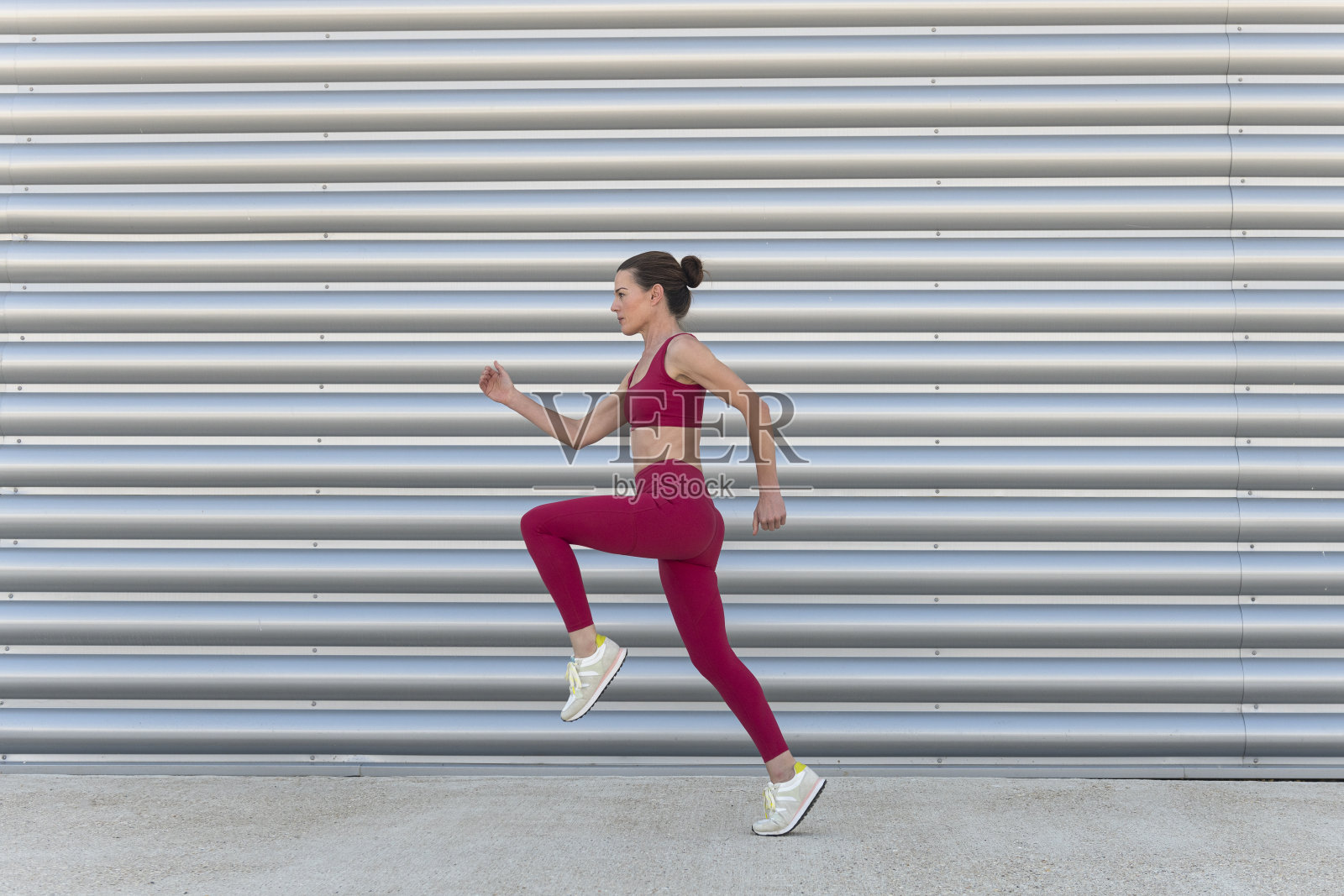 在城市背景下跑步的运动型女人,身穿红色运动服照片摄影图片