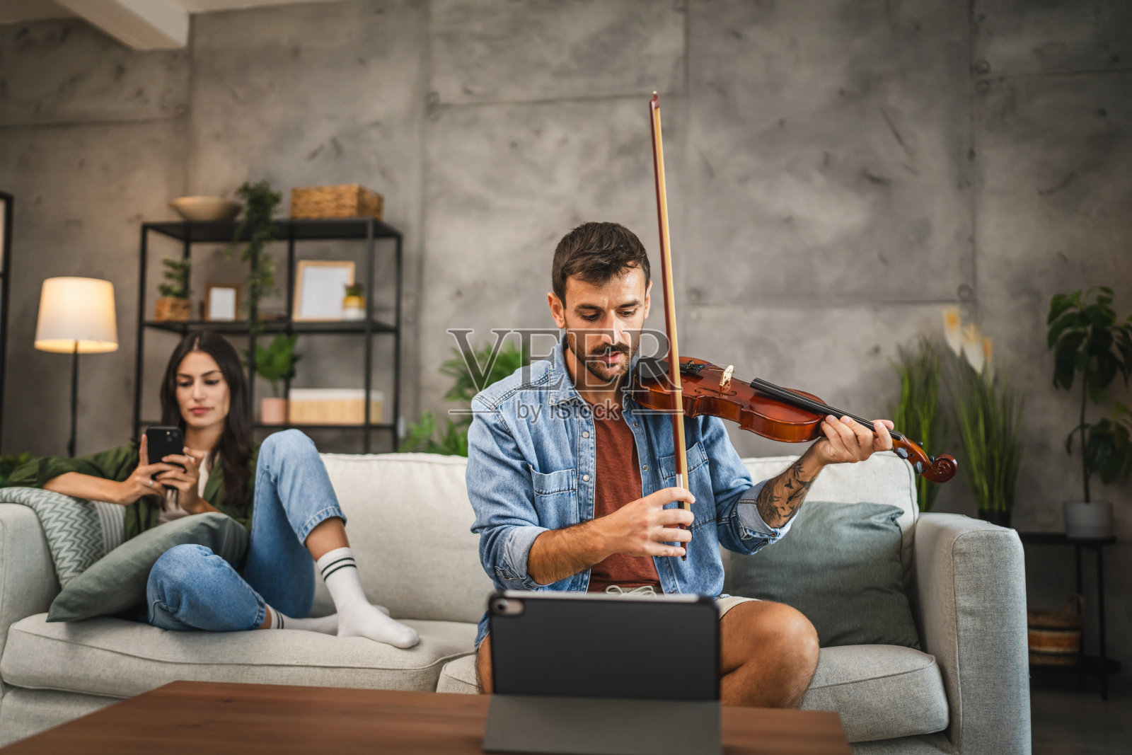 成年男子在家里用平板电脑学习如何拉小提琴照片摄影图片