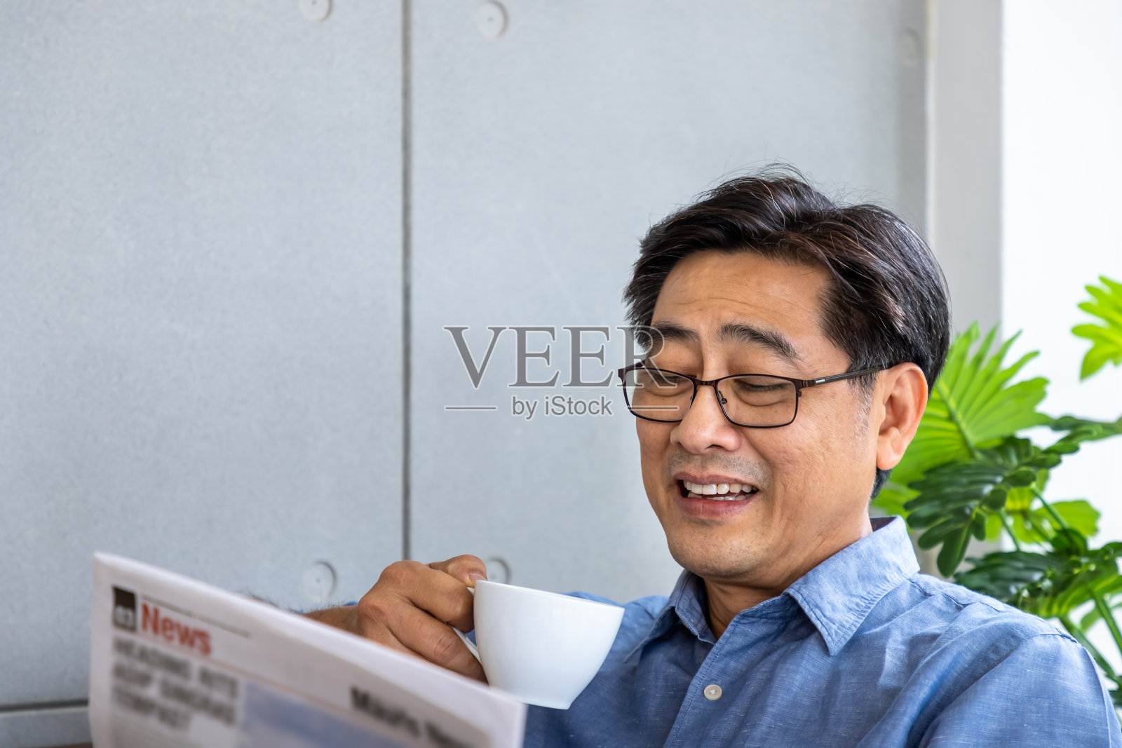 在家里看报纸喝咖啡时微笑的亚洲老人照片摄影图片