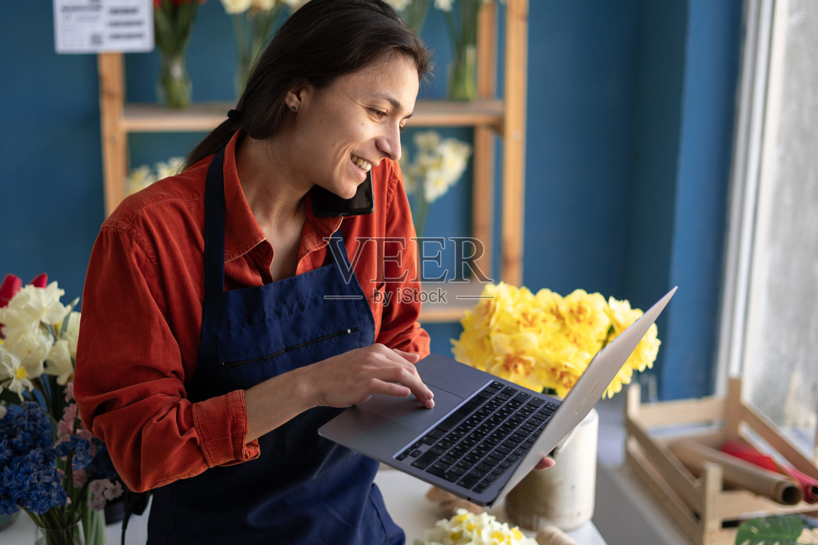 花店小生意花店老板。女人用智能手机和笔记本电脑为她的商店接受客户订单。自己的业务照片摄影图片