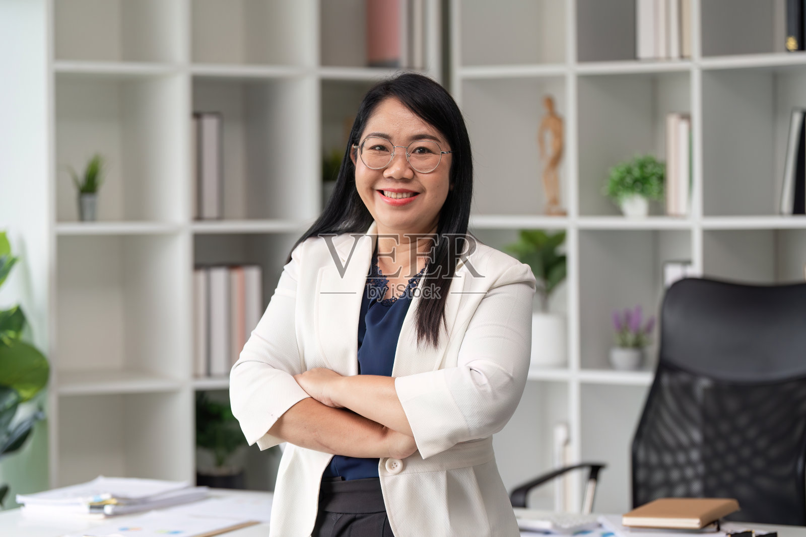 在现代办公环境中,自信的女商人双臂交叉,微笑着看着镜头照片摄影图片