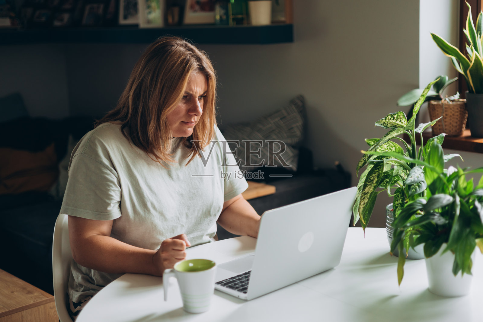 沮丧的年轻成年女性在家里翻看笔记本电脑。消极的人的情绪,女性自由职业者在家办公的工作场所。照片摄影图片
