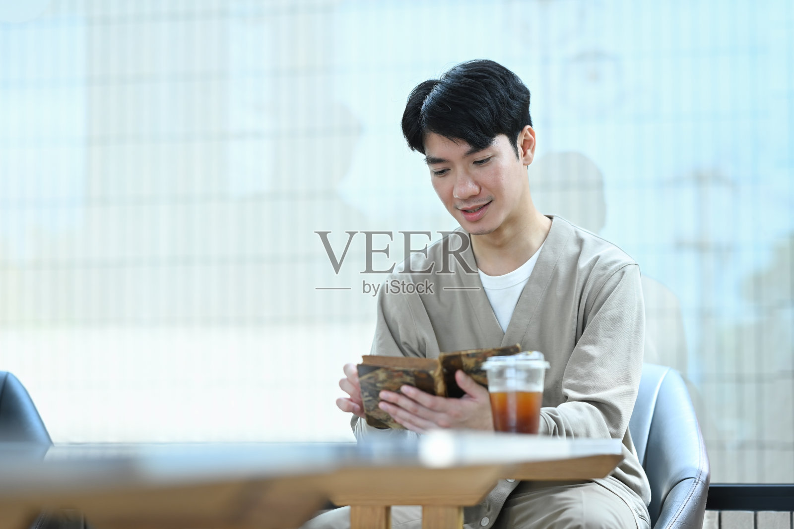 安静的年轻亚洲人一边在咖啡馆放松一边看书照片摄影图片