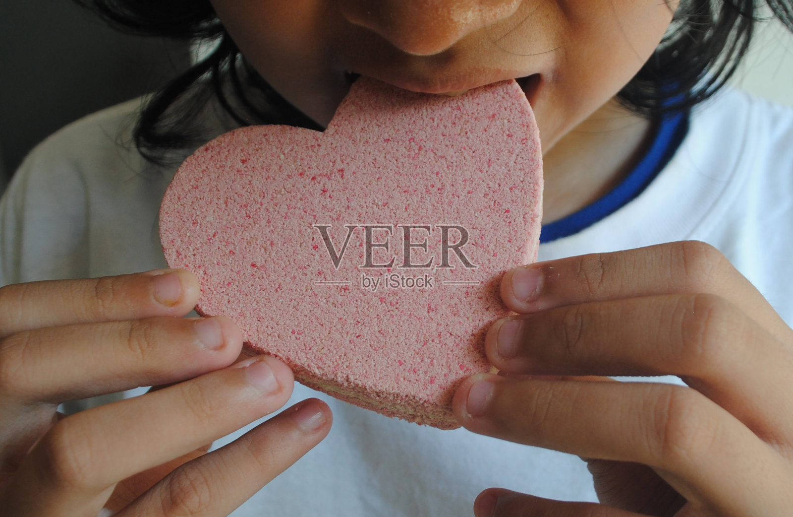 女孩吃心形标志的特写。照片摄影图片