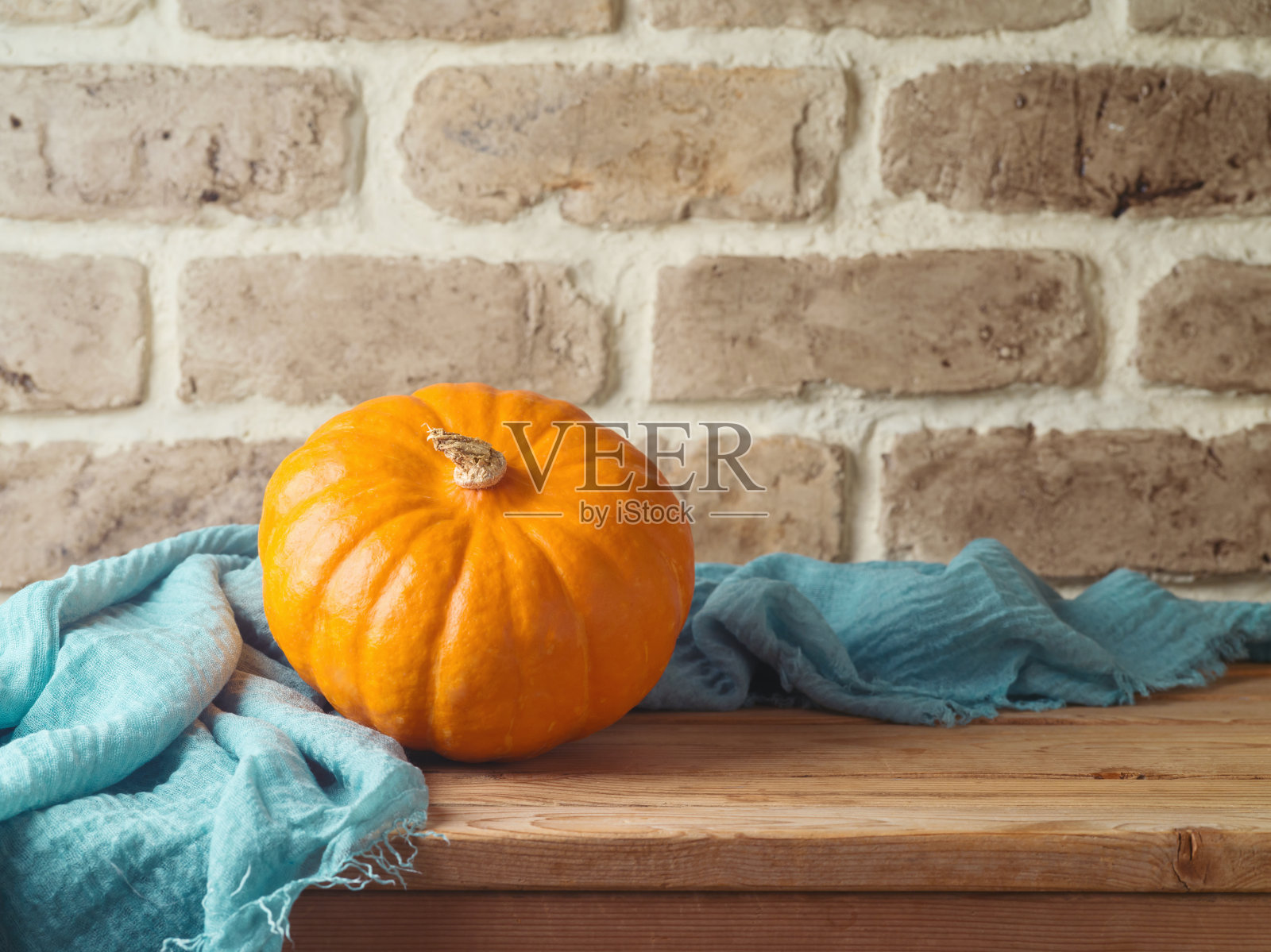 秋天的概念与橙色南瓜在砖墙背景木桌上。感恩节贺卡照片摄影图片