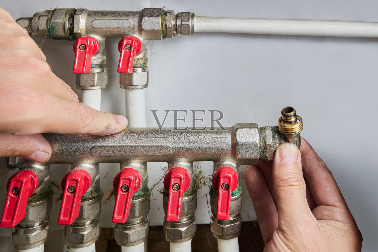 水管工正在为有五个出水口的塑料管安装歧管。照片摄影图片