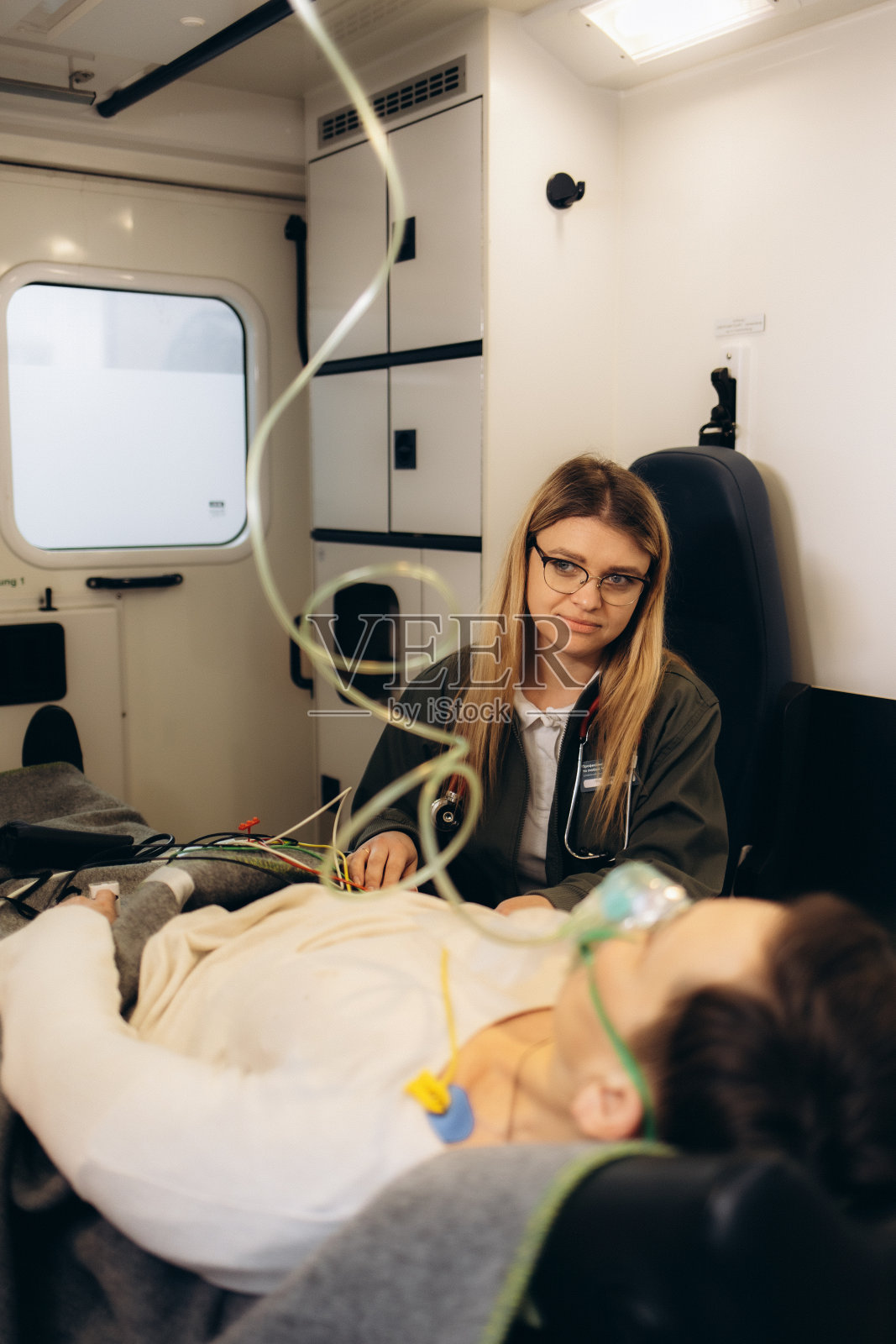 女急救专业护理人员在去医院的路上安慰受伤的病人。救护车上的急救助理友好地把手放在受害人的肩膀上。照片摄影图片