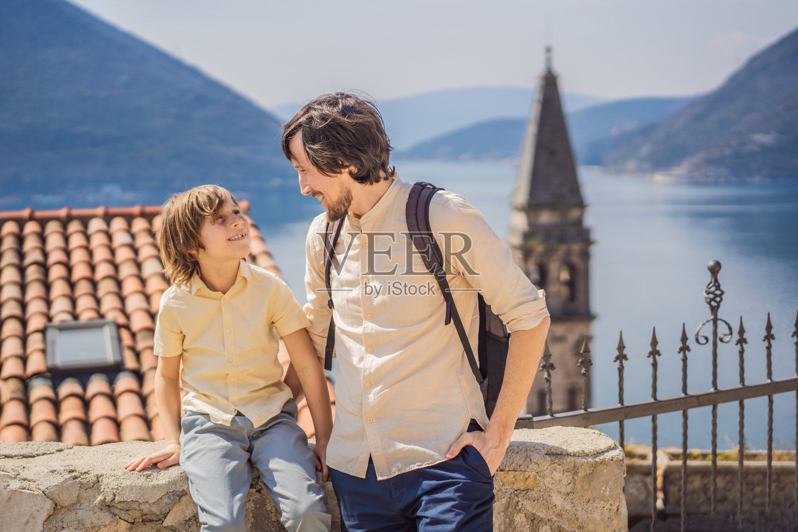 在一个阳光明媚的日子里,爸爸和儿子在黑山的佩拉斯特老城享受五彩缤纷的街道。黑山旅行的概念。在一个美丽的阳光明媚的日子里,蓝天白云,著名的科托尔湾的历史小镇佩拉斯特的全景景色照片摄影图片