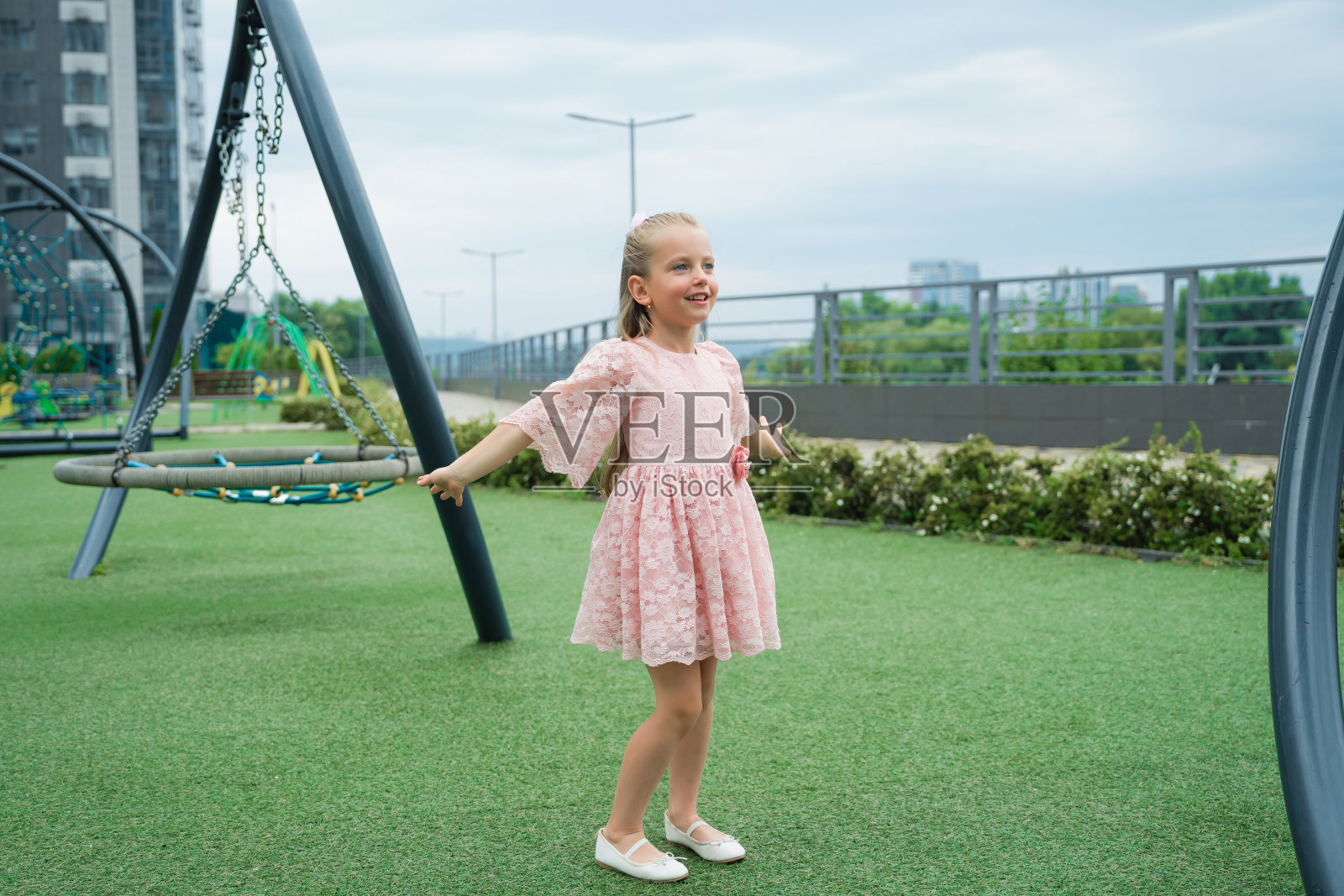 一个小女孩在一个阴天的现代城市操场上快乐地玩耍照片摄影图片