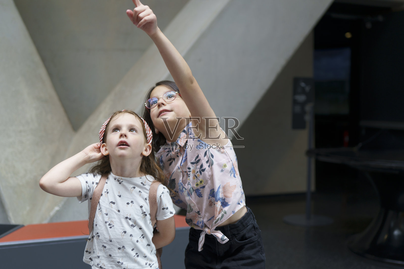 两个可爱美丽的女学生惊讶而感兴趣地抬头看向博物馆。儿童教育理念照片摄影图片