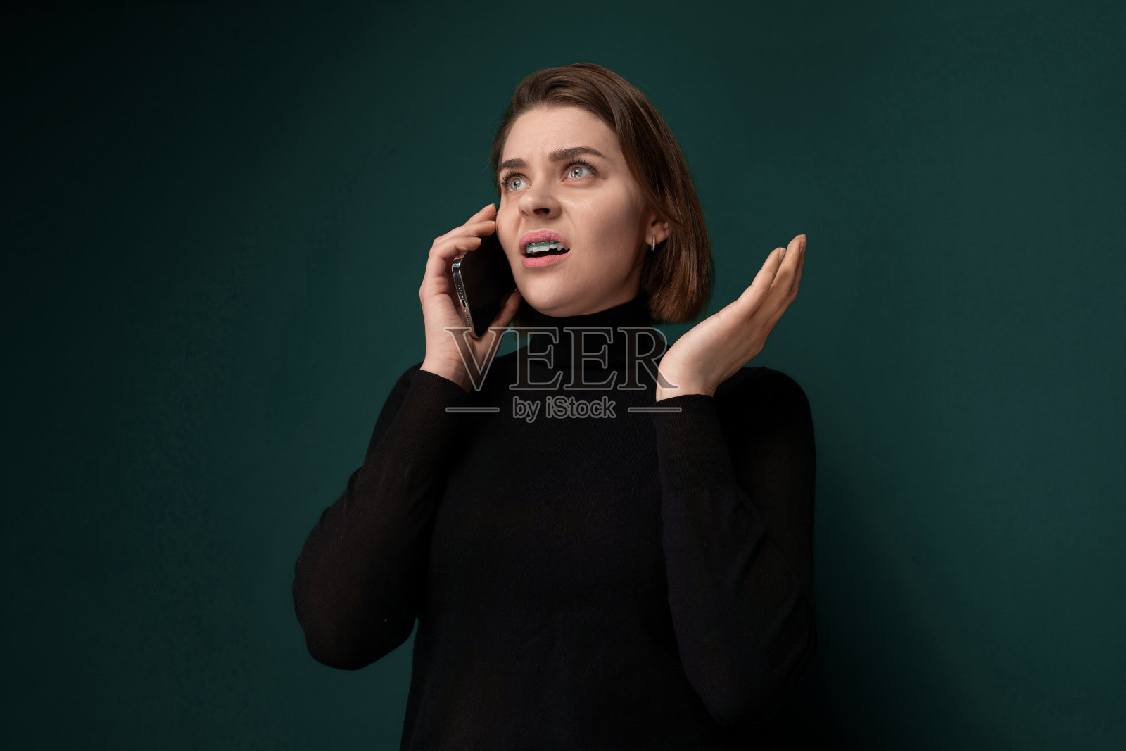 对着绿墙讲手机的女人照片摄影图片