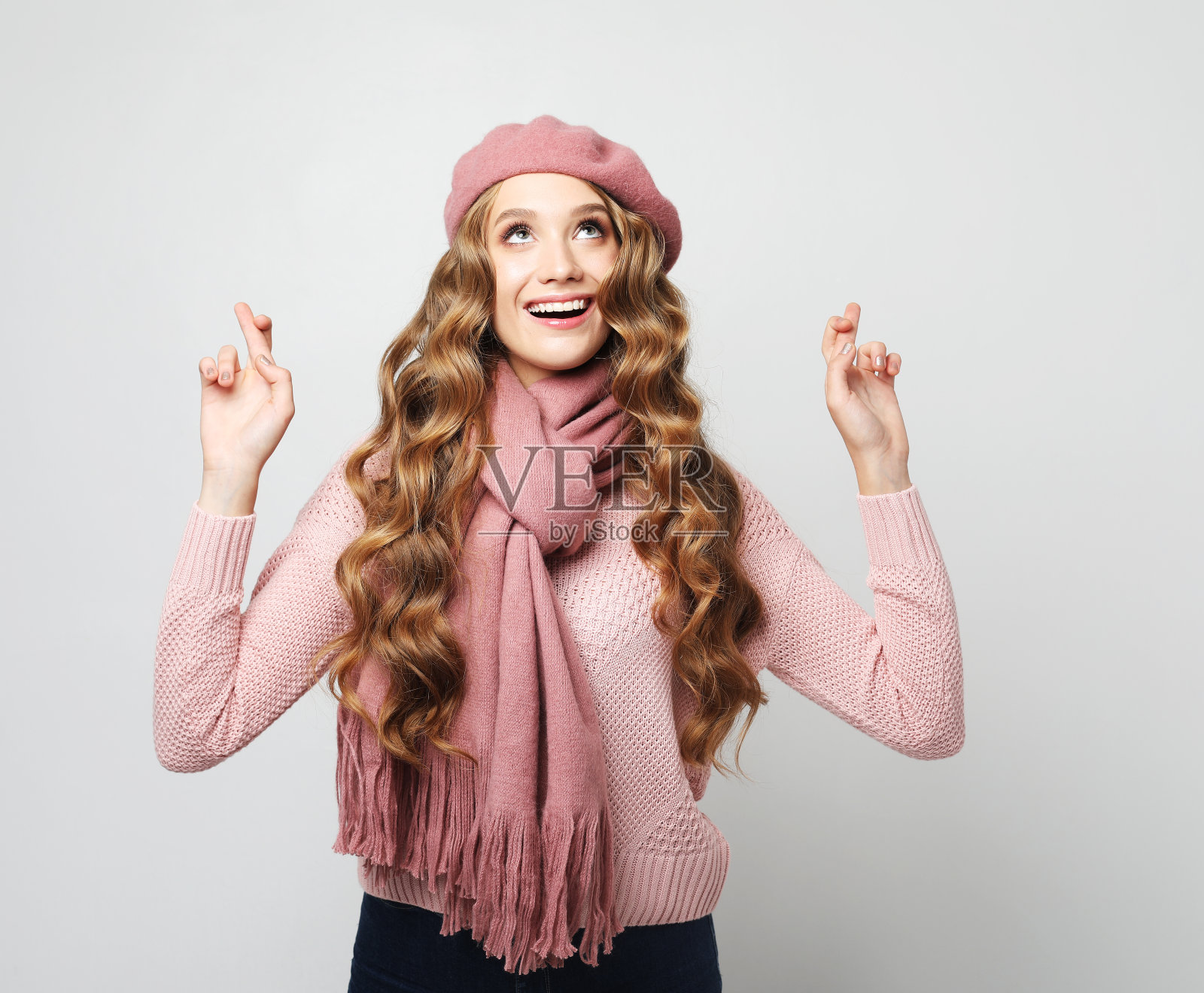 乐观的金发女子在灰色的背景下交叉手指,希望梦想成真照片摄影图片