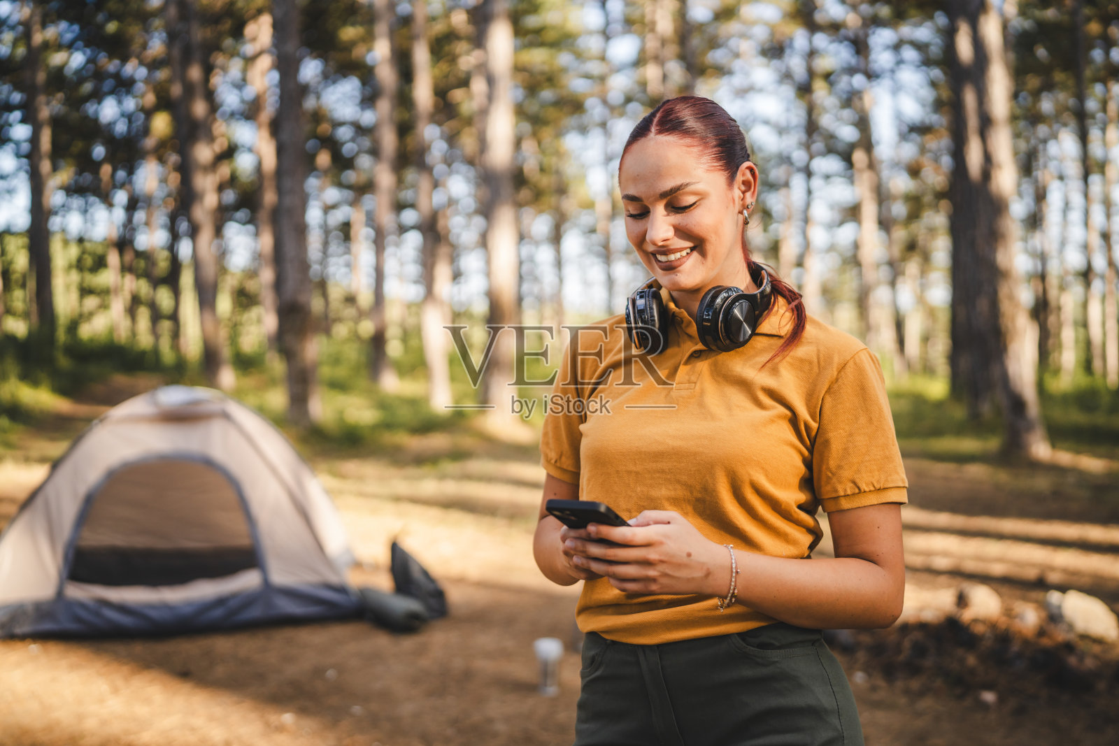 年轻女子的肖像,戴着耳机,使用手机照片摄影图片