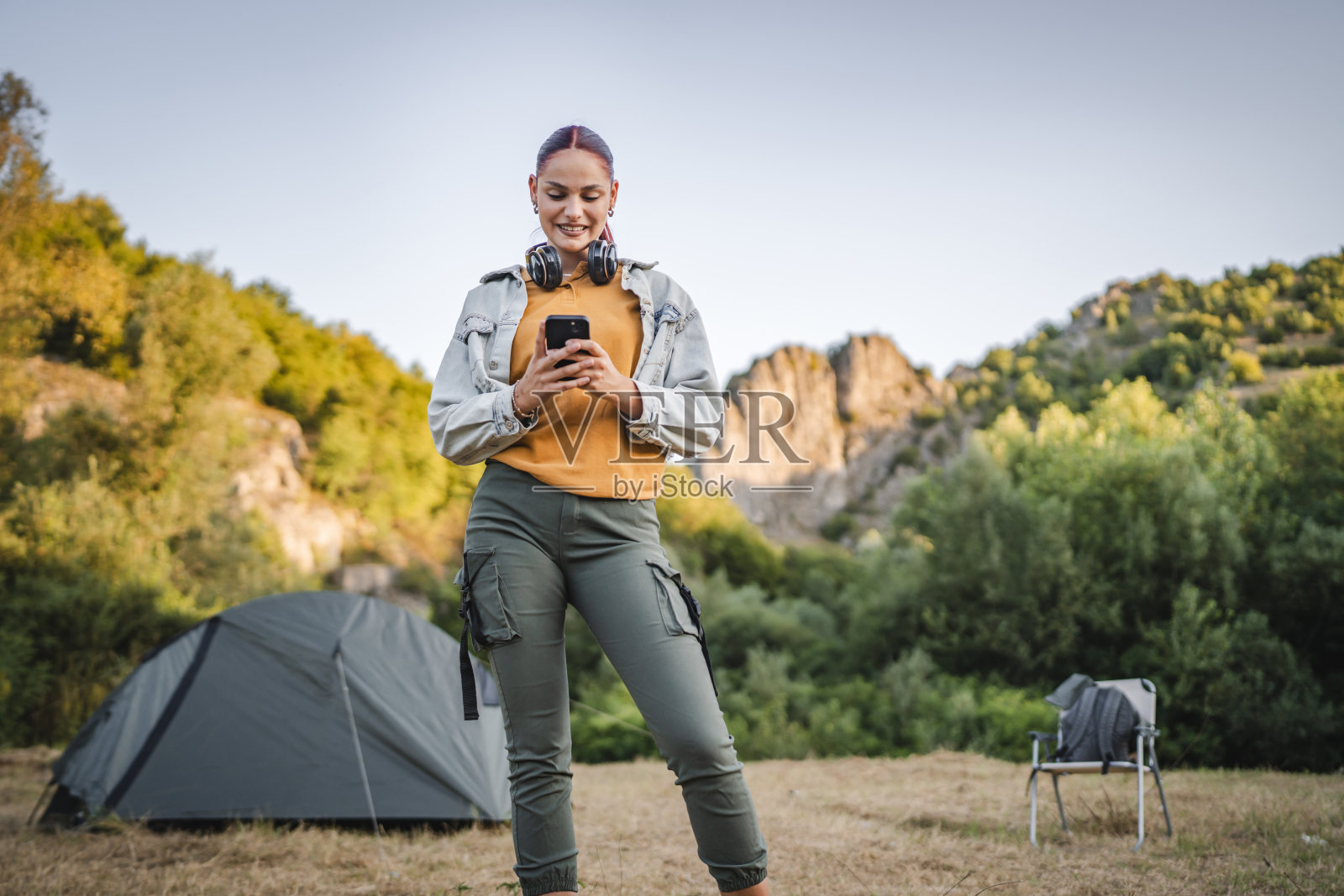 年轻女子的肖像,戴着耳机,使用手机照片摄影图片