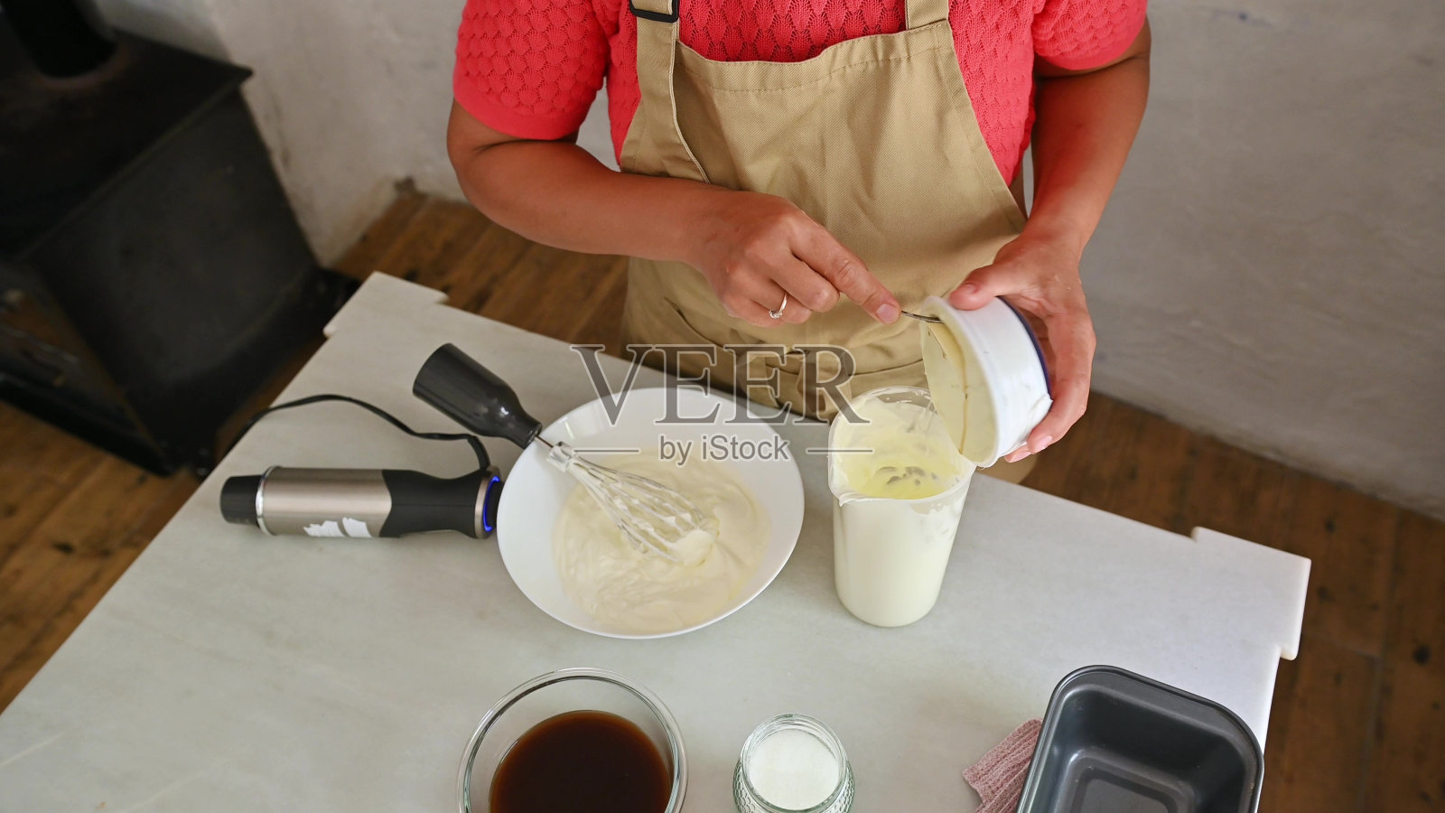 妇女在厨房用奶油和打蛋器准备意大利甜点照片摄影图片