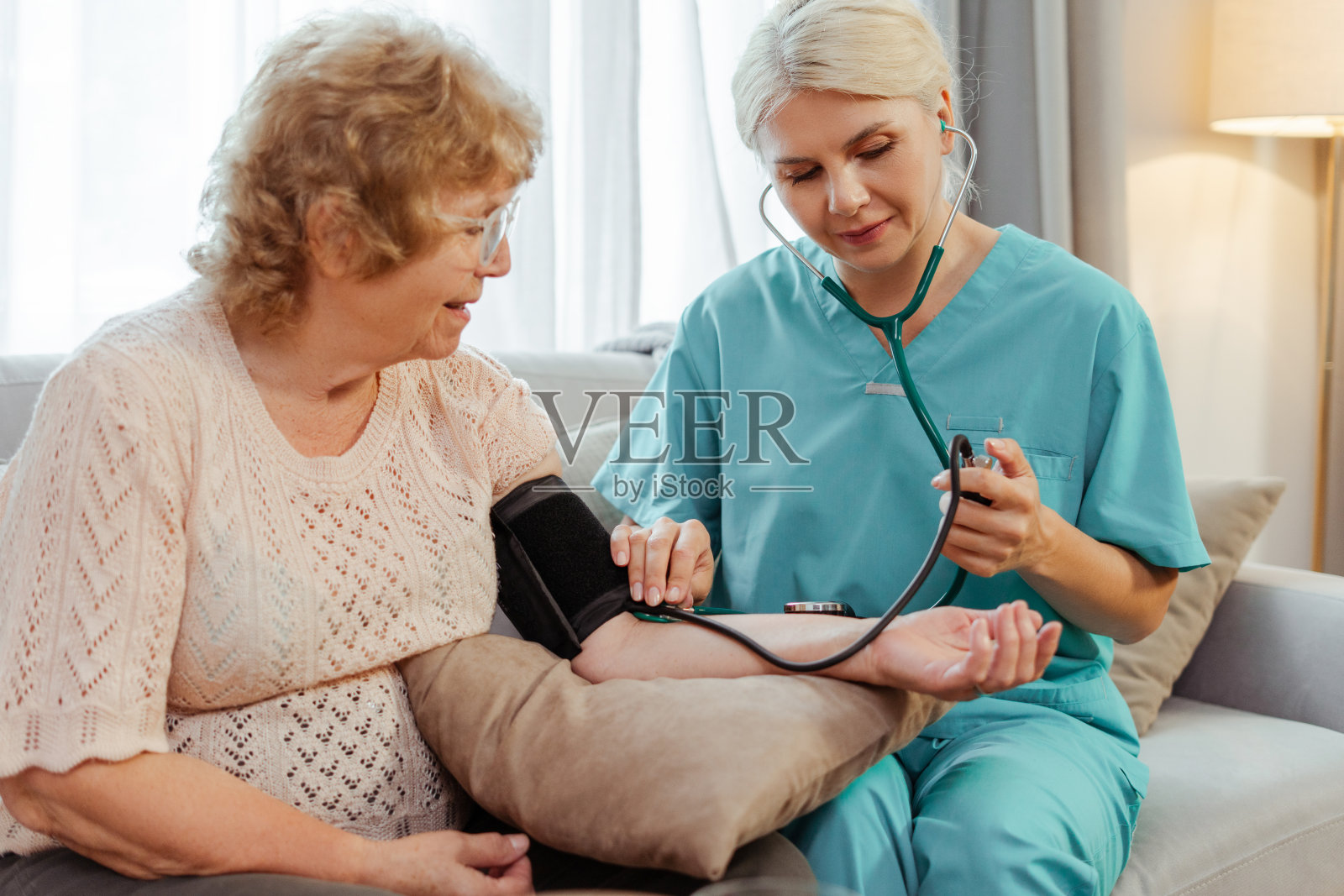 护士在家里给一位面带微笑的老妇人量血压照片摄影图片