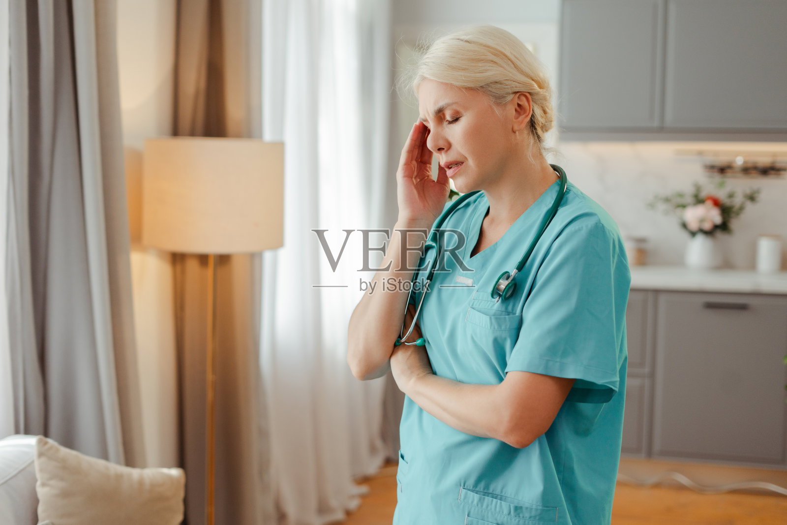 疲惫不堪的女医生在家里头痛照片摄影图片