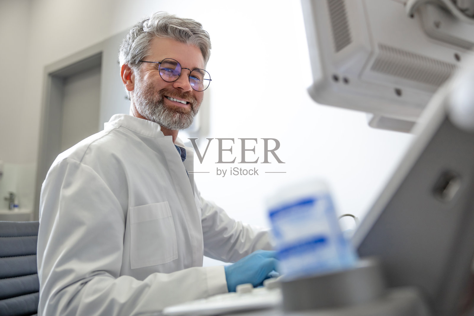 头发花白的男医生在超声诊断仪前工作照片摄影图片