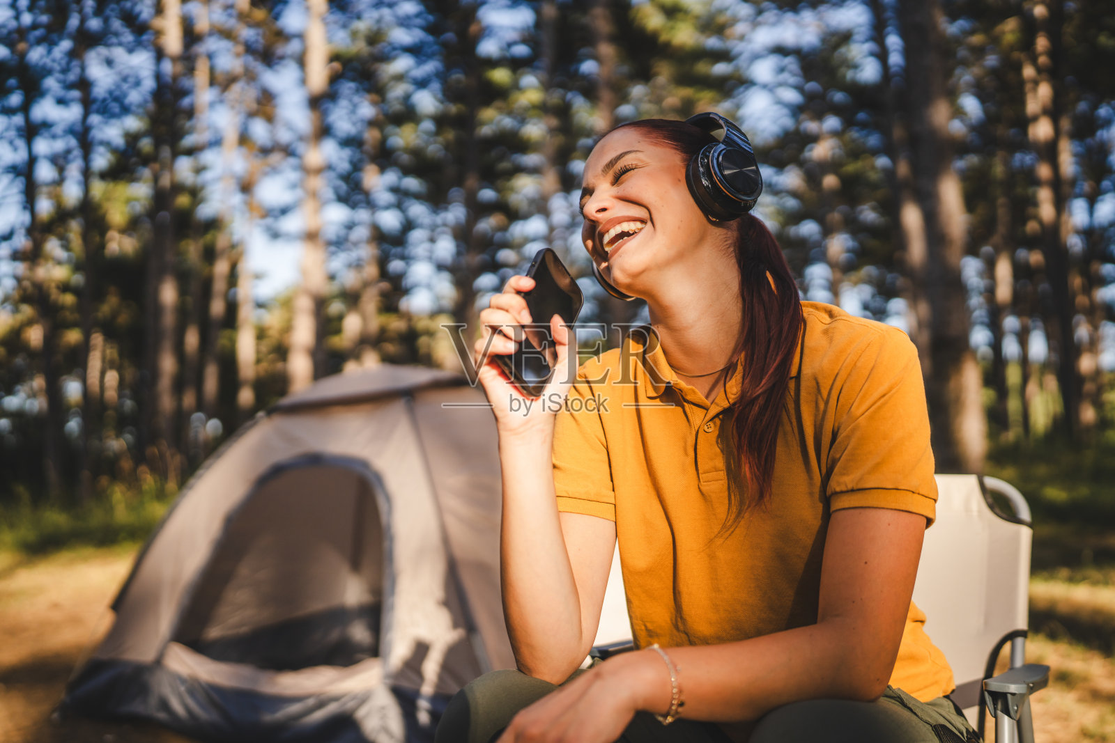 戴着耳机的年轻女子坐在台前,一边听音乐一边唱歌照片摄影图片