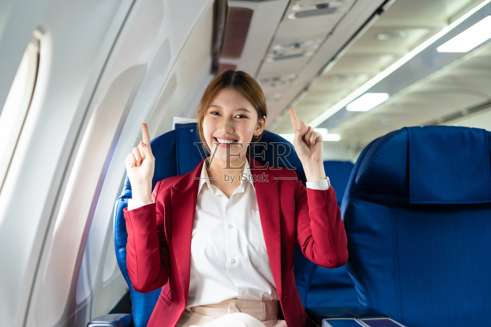 快乐的女人乘飞机旅行,女人的肖像与旅途乘客靠近窗口。照片摄影图片