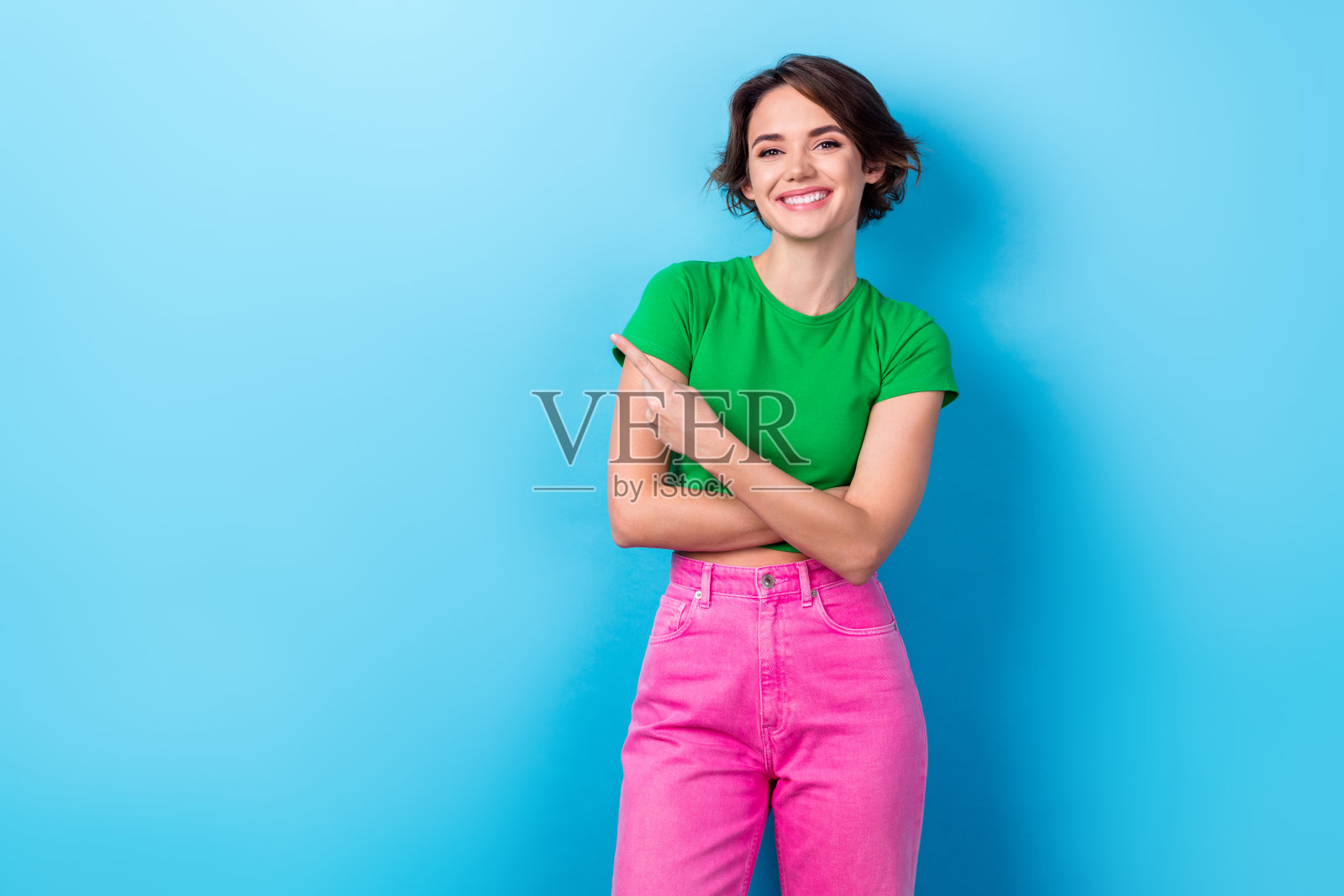 照片的好心情的女商人穿绿色的t恤,粉红色的裤子直接手指模拟像新的时尚杂志孤立的蓝色背景照片摄影图片