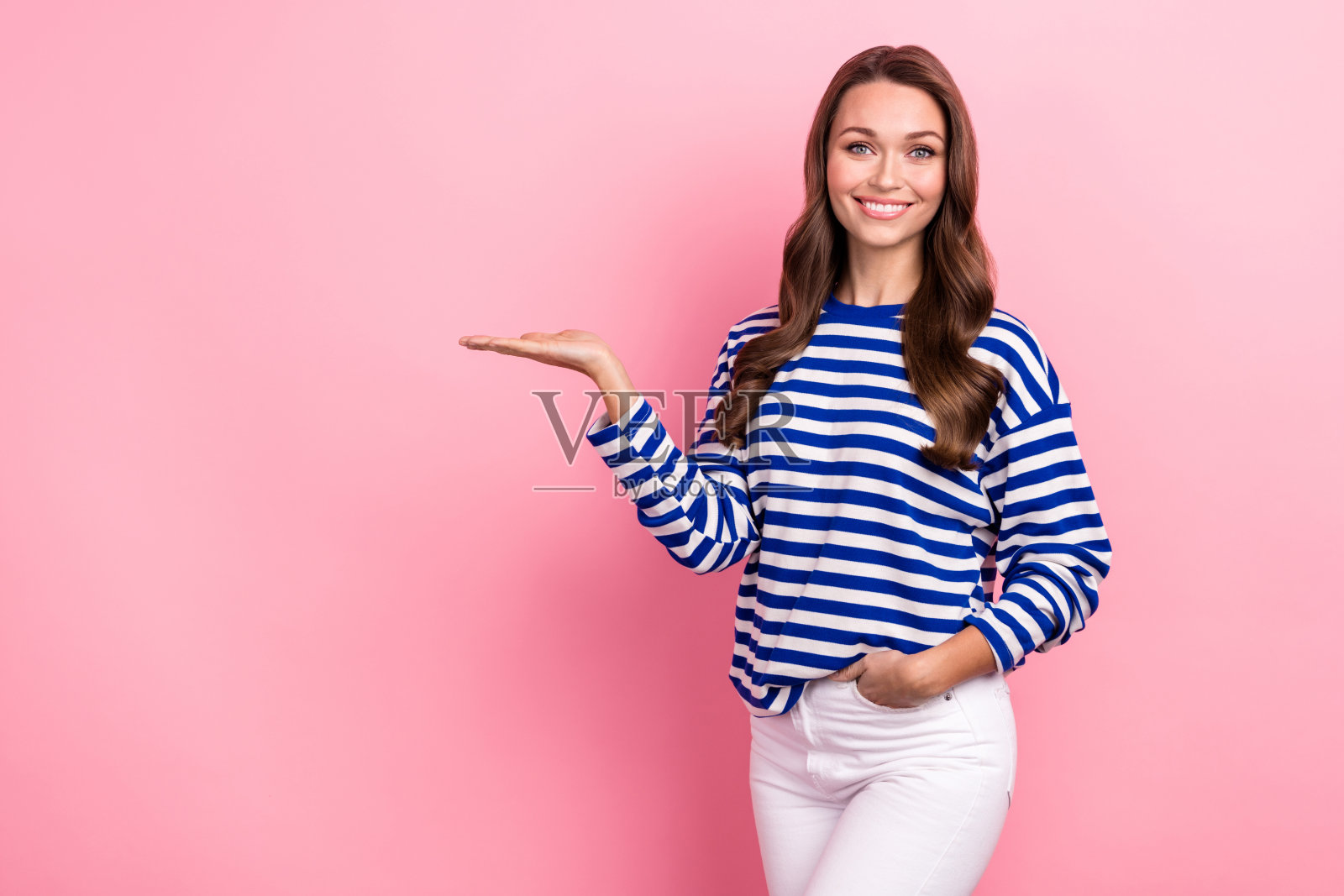 照片华丽乐观的女人波浪发型条纹衬衫手掌示范产品空白空间孤立在粉红色的背景照片摄影图片