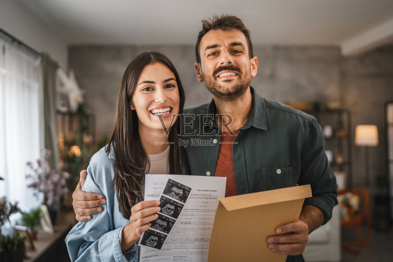 成年夫妇站着,拿着婴儿和信封的超声波照片照片摄影图片