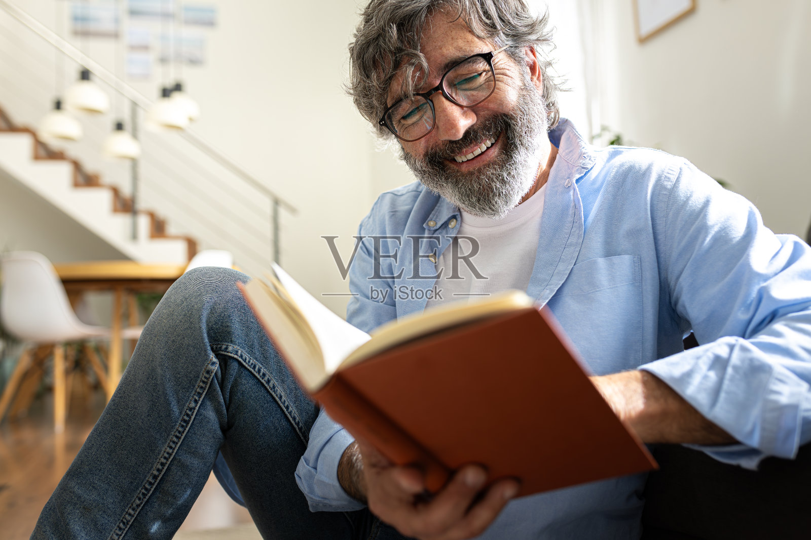 快乐的成熟男人戴着眼镜在家放松看书。照片摄影图片