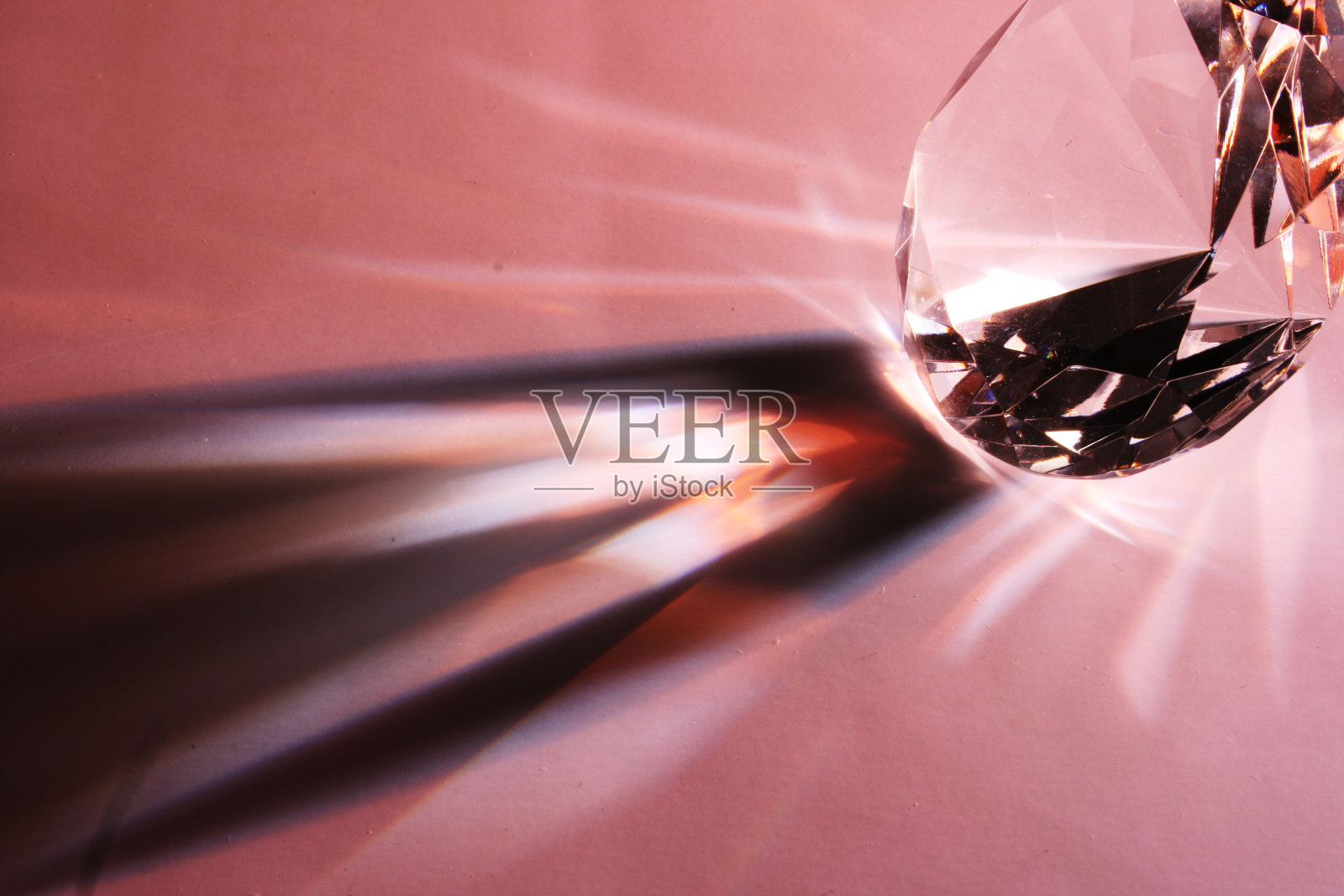 粉色桌子上带有阴影图案的钻石特写照片摄影图片