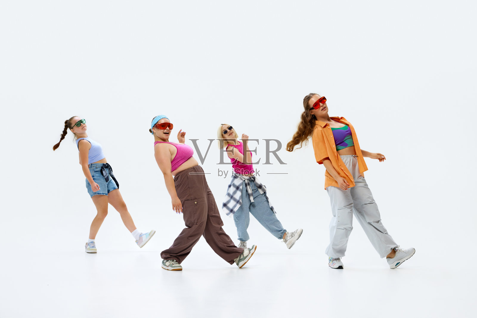 舞者们穿着时髦的彩色服装,戴着太阳镜,摆出协调的姿势,在白色的工作室背景下散发出自信和才华。照片摄影图片