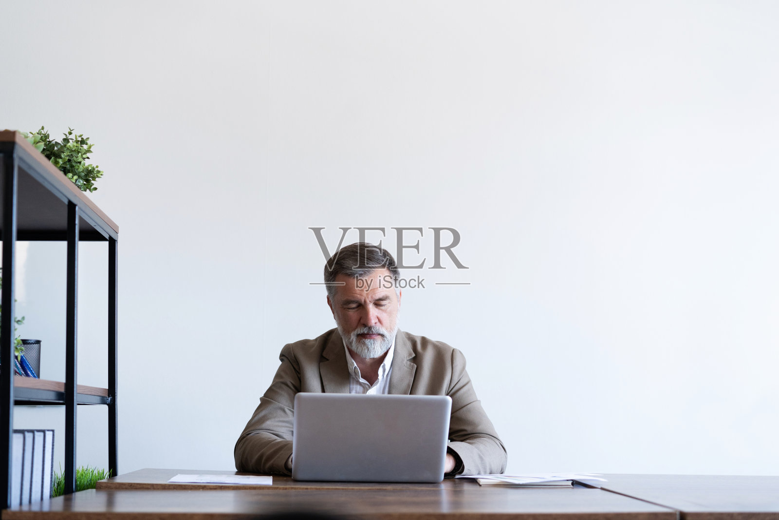 一个成熟的男人坐在现代办公室的办公桌前。照片摄影图片