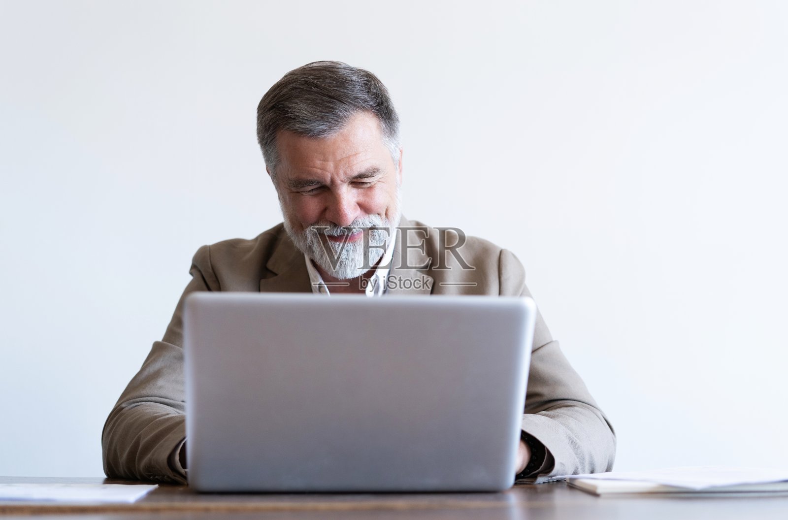 一个成熟的男人坐在现代办公室的办公桌前。照片摄影图片