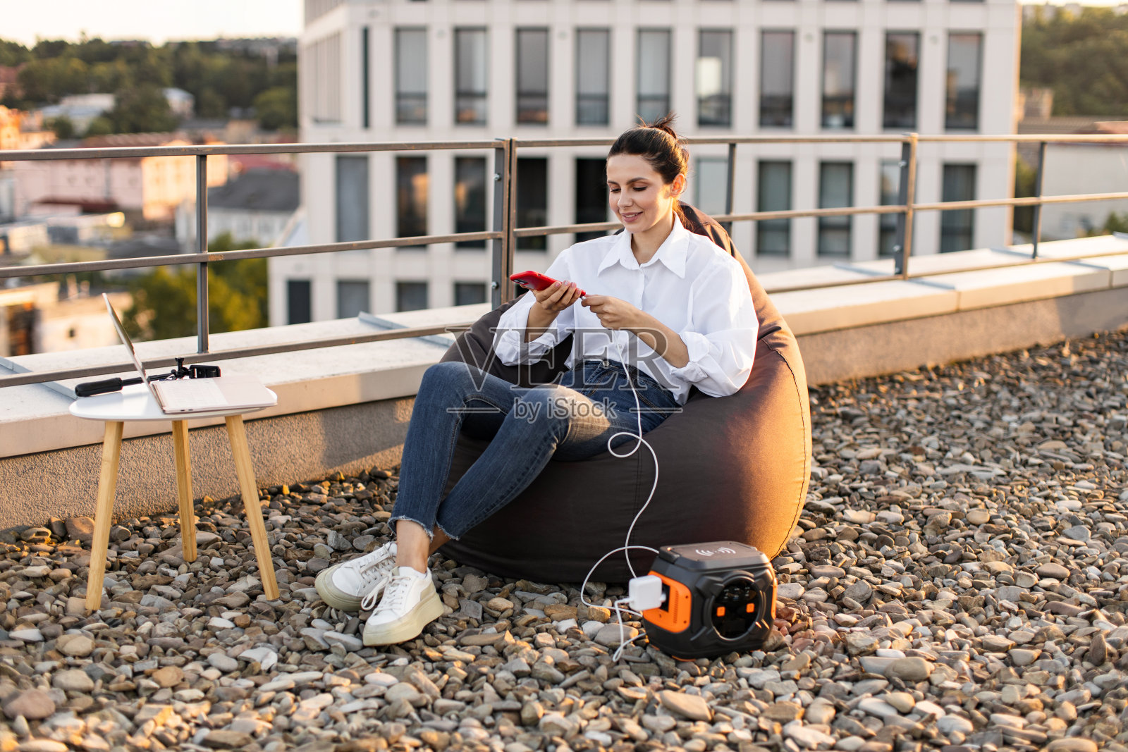 女商人在屋顶上带着便携式发电站休息照片摄影图片