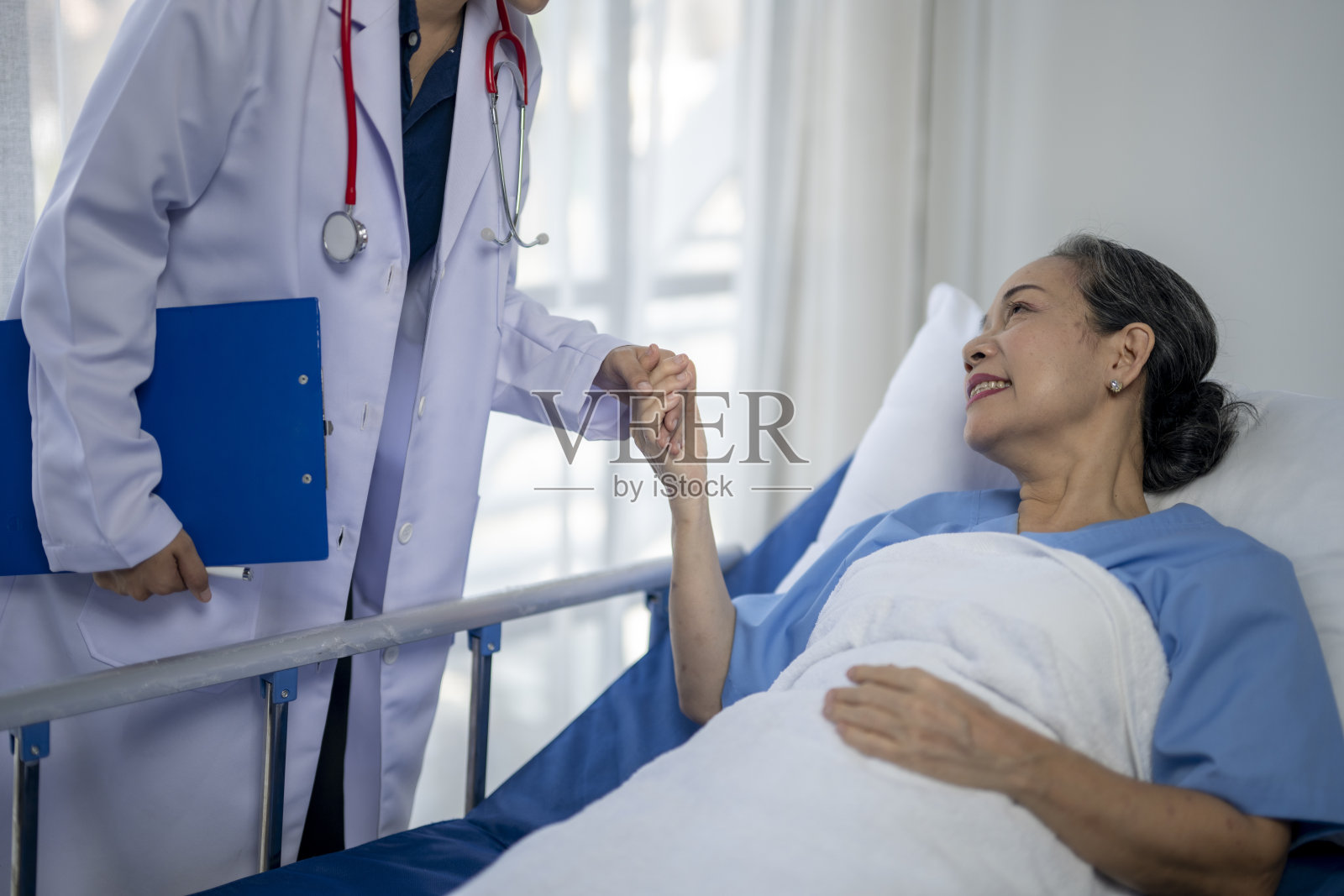 一个女人躺在医院的病床上,医生握着她的手照片摄影图片