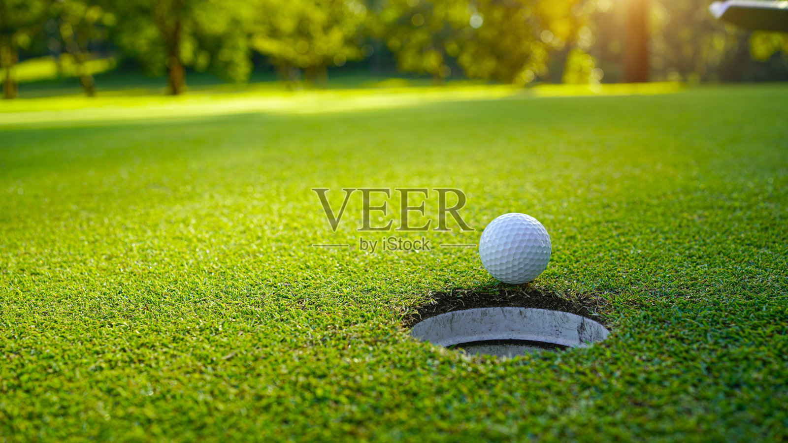 高尔夫球在一个美丽的高尔夫球场的绿色草坪上,早晨阳光明媚。照片摄影图片