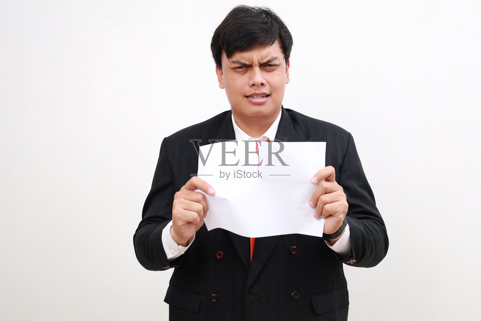 紧张的年轻亚洲商人撕开空白纸,孤立在白色的背景上照片摄影图片