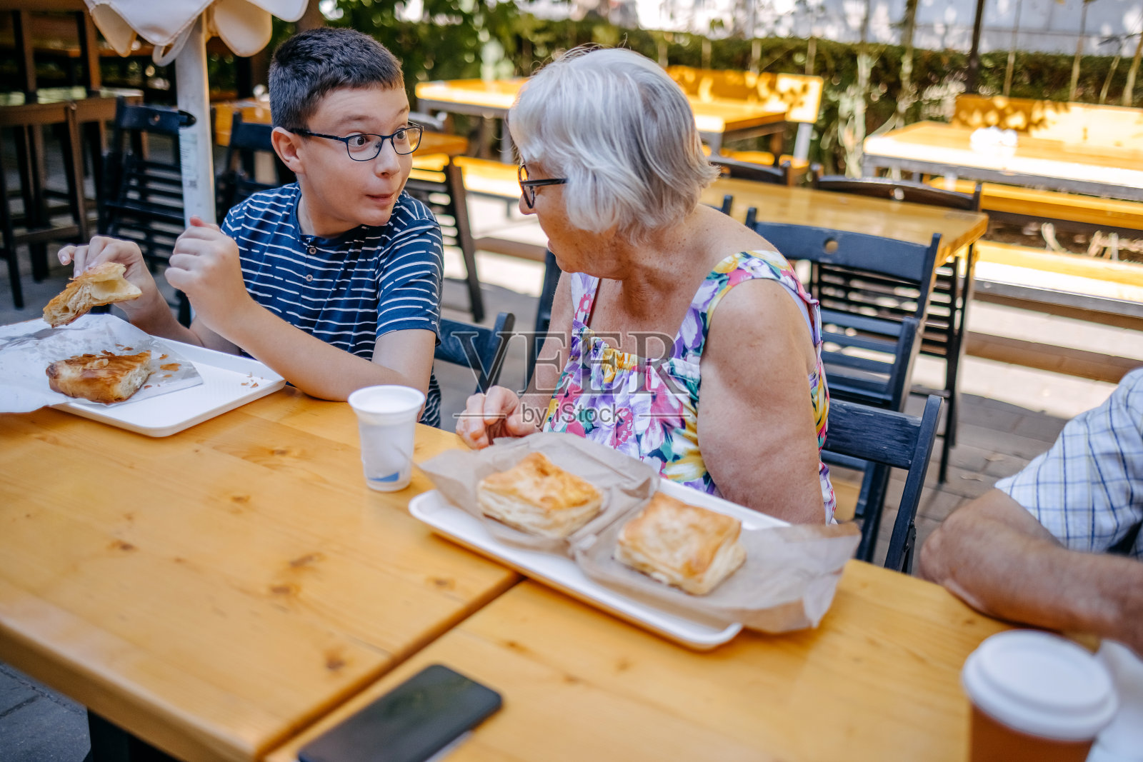 青少年和祖父母一起坐在面包店前吃早餐照片摄影图片