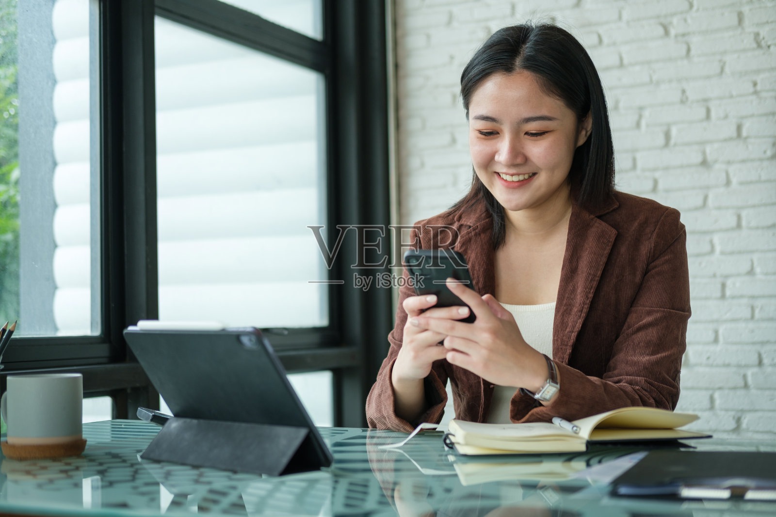 亚洲女性员工查看社交媒体,用智能手机阅读在线新闻。照片摄影图片