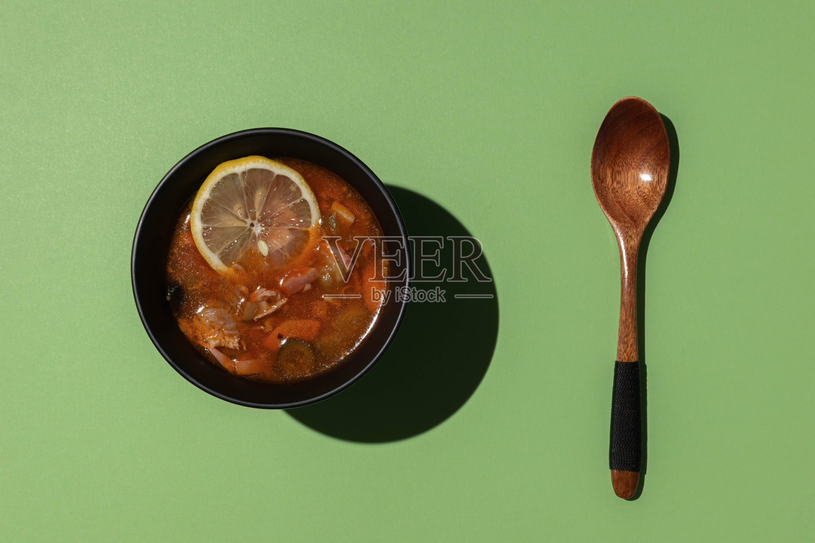绿底木勺上盛着柠檬片的热汤俯视图照片摄影图片