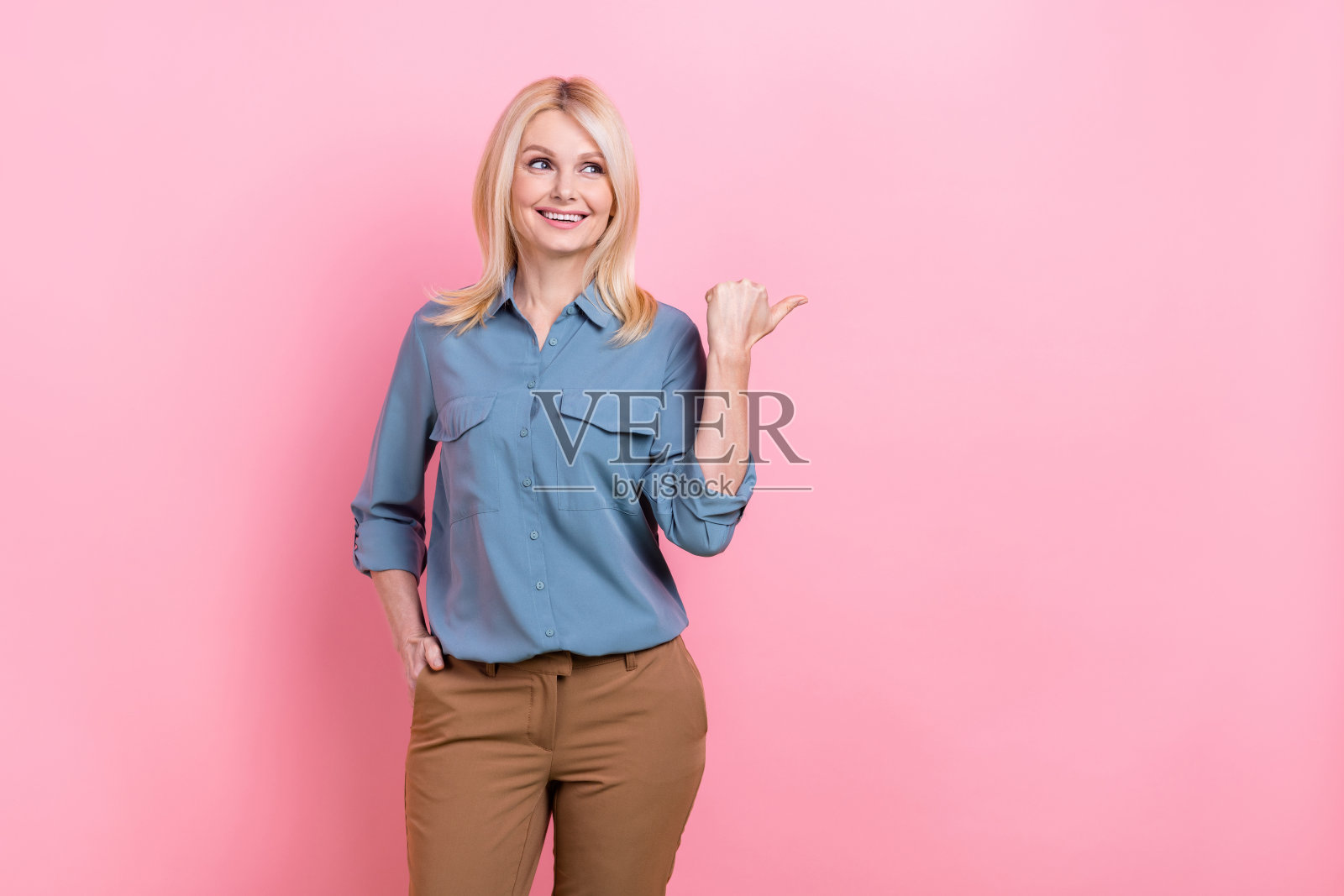 照片中迷人的退休商业女士直接空出空间,海报上穿着时髦休闲的办公服装,背景是孤立的粉红色照片摄影图片