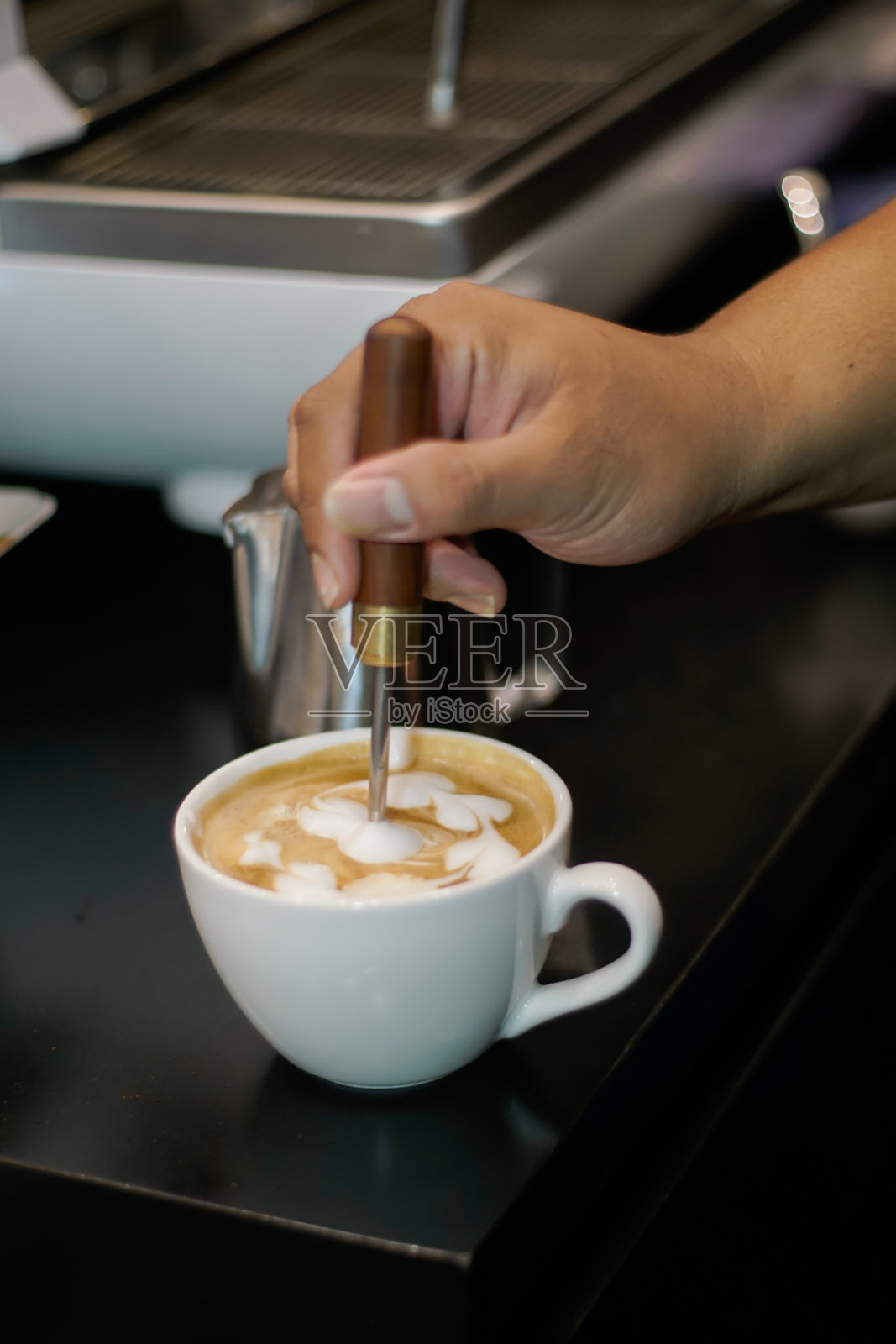咖啡师在拿铁上制作泡沫艺术照片摄影图片
